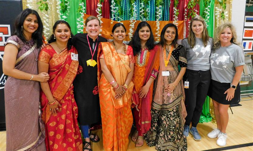 A group of adults stands together in front of a green and red backdrop